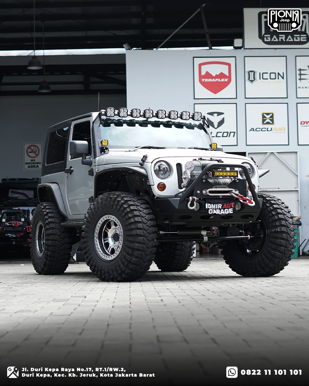 Jeep Wrangler Rubicon JK warna silver 2 pintu dengan modifikasi offroad monster dan lampu sorot LED Baja Designs XL di Pionir Auto Garage